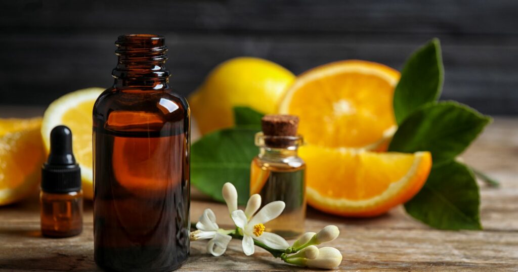 Essential oils and oranges on a wooden table. Featuring Orange Essential Oil.