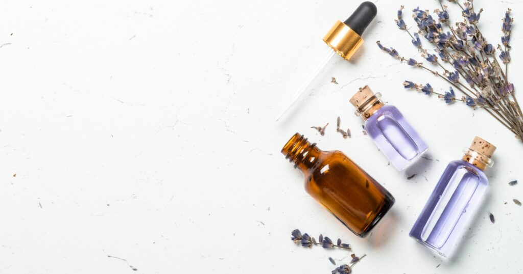 A collection of lavender essential oil bottles and dried lavender flowers on a white surface.