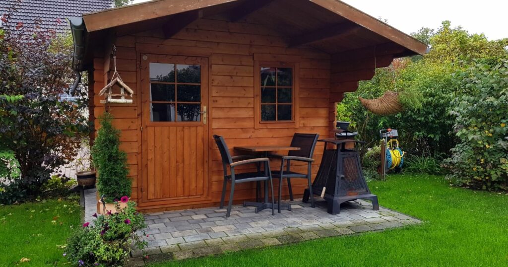 A modern garden shed with a cozy setup of a table and chairs, providing a tranquil outdoor space.